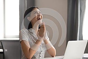 Happy excited Asian businesswoman puts hands in prayer, thanking fate