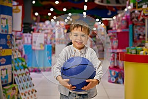 Happy excited boy child with ball during shopping in mall