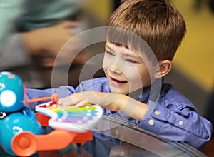 Happy excited boy in a department store / shopping mall testing interactive toys and choosing a christmas present. Black friday