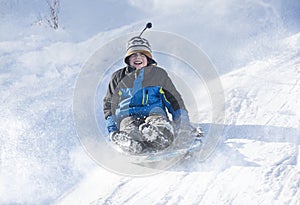 Happy and excited boy Sledding downhill on a snowy day