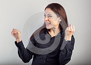 Happy excited business woman showing success triumph sign by fist and loud shouting with open mouth on blue background with empty