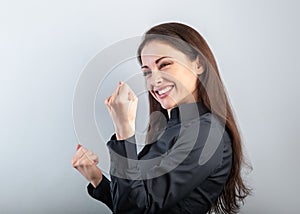 Happy excited business woman showing success triumph sign by fist and loud shouting with open mouth on blue background with empty