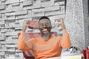 Happy excited businessman celebrate his success. Winner, black man in office reading on laptop, copy space