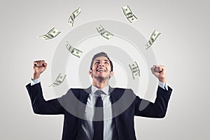 Happy excited businessman raising hands up and looking up under money rain