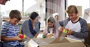 Happy, excited and carefree family unpacking boxes after moving house, relocating or buying a home. Parents and children
