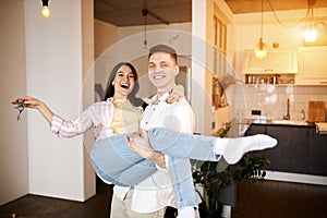 Happy excited cheerful couple celebrating new home,holding keys in hands