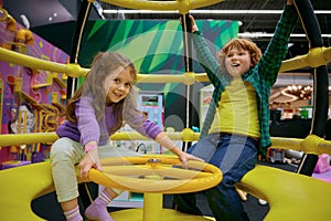 Happy excited children playing on indoor carousel at play center