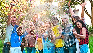 Happy excited friends having fun outdoor celebrating with confetti - Young millenial people enjoying summertime together at garden