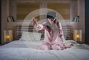 Happy and excited girl playing with virtual reality VR goggles headset device having fun on bed having 3D experience with video