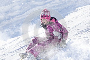 Happy and excited girl Sledding downhill on a snowy day