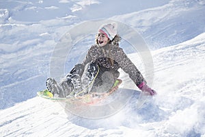 Happy and excited girl Sledding downhill on a snowy day