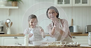 Happy excited grandma and grandkid girl having fun in kitchen