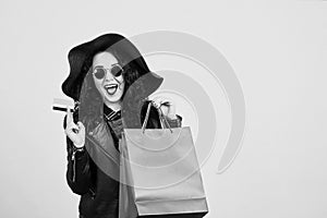 Happy excited hipster woman in sunglasses holding credit card and colorful shopping bags. ?heerful woman looking at camera, isolat