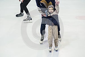 Happy little boy and his mother learning ice-skating
