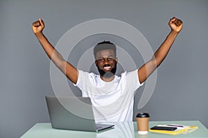 Happy excited man celebrate his success. Winner, black man in office reading on laptop, copy space