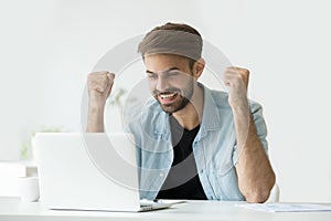 Feliz entusiasmado hombre celebra conectado a internet ganar consecuencia mira a notas 