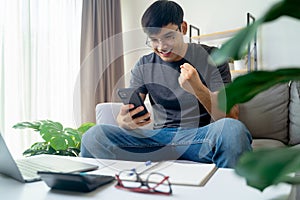 Happy excited man looking at mobile phone, man receiving good news using smartphone at home