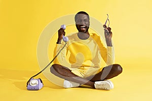 Happy excited man with phone celebrating on yellow background