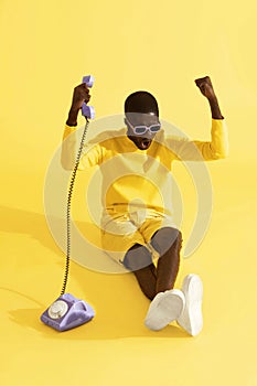 Happy excited man with phone celebrating on yellow background