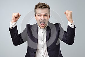 Happy excited man in suit screaming and celebrating succcess with two fists up