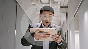 Happy excited middle-aged Asian businessman chinese korean japanese man with digital tablet win business success bet