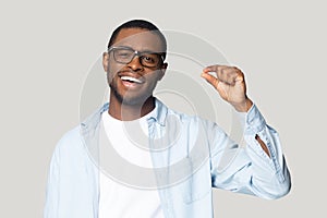 Happy excited millennial african american guy showing small prices gesture.