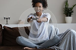 Happy excited millennial Black girl playing video game at home