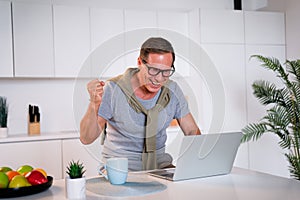 Happy excited old elderly man winner excited by reading good news looking at laptop, overjoyed senior mature grandfather