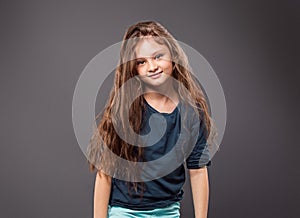 Happy excited positive kid girl with long hair on grey background with empty copy space. Closeup