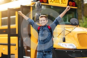 Happy Excited Preteen Boy Raising Arms While Standing Near Yellow School Bus