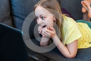 Happy excited preteen girl chatting online using laptop for video call.