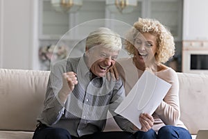 Happy excited senior retired couple reading paper document