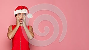 Happy excited shoÑked Christmas woman Santa posing against bright pink studio wall background. Xmas offer and gift concept