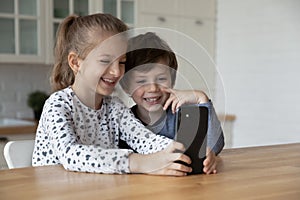 Happy excited sibling gen Z kids using smartphone together