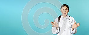 Happy and excited smiling young woman looking with excitement and surprised, standing in white lab coat and stethoscope