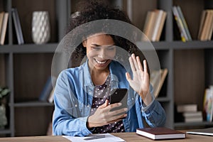 Happy excited student girl in waving hand hello at smartphone