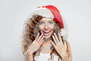 Happy excited surprised young woman in Santa hat smiling. Christmas and New Year party portrait