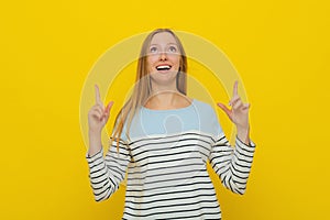 Happy excited woman with fair-haired gestures with hands, pointing fingers up to show best deal, showing advertisement with amused