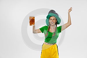 Happy excited woman in green yellow football kit holding beer mug and football ball supports favorite team. Soccer fans