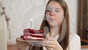 Happy excited woman making cherished wish and blowing candles on holiday cake, smiling to camera, celebrating birthday
