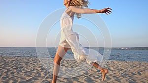 Happy excited woman running and jumping on the beach in slow motion