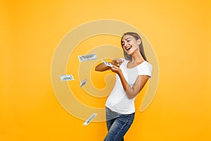 Happy excited woman throws money on yellow background