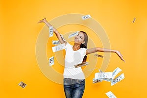 Happy excited woman throws money on yellow background