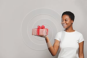 Happy excited woman in white t-shirt holding gift box surprise against white studio wall banner background