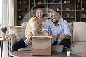 Happy excited young African couple receiving parcel