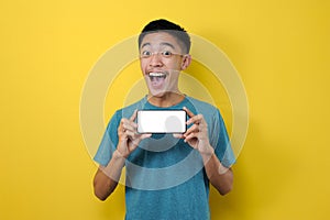Happy Excited Young Asian man showing white phone screen at camera