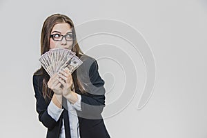 Happy excited young business woman is showing a pile of money, isolated on white background. Girl is satisfied by huge