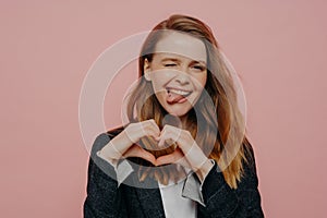 Happy excited young woman showing heart shape sign