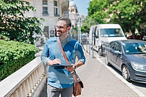 Happy executive using digital tablet while walking on sidewalk during sunny day