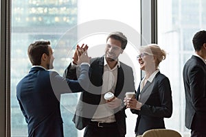 Happy executives give high five during friendly talk in office